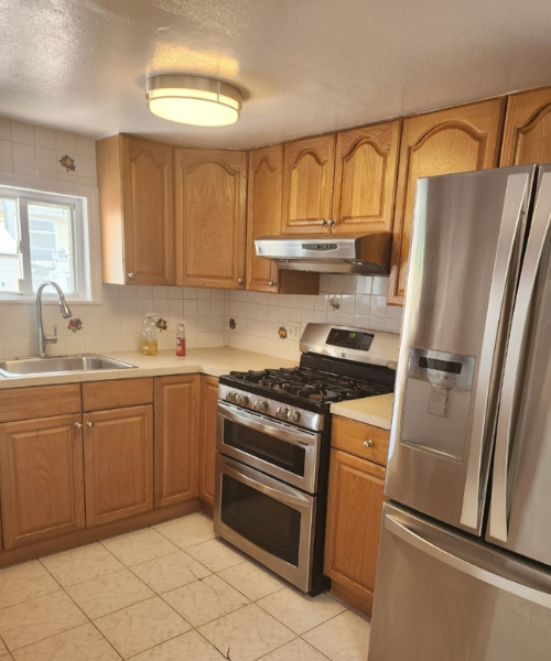 A kitchen with a stove, refrigerator and sink