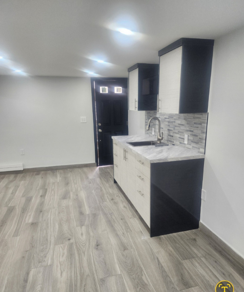 A kitchen with white cabinets and a black sink