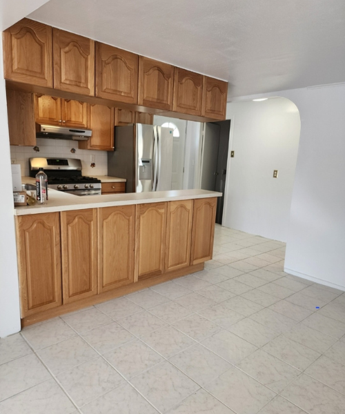 A kitchen with a refrigerator and a stove top oven